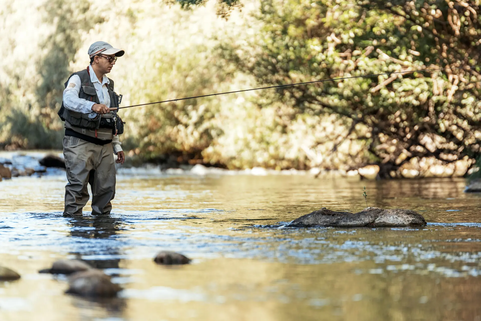 Fishing guide casting beside a wooded Scottish river