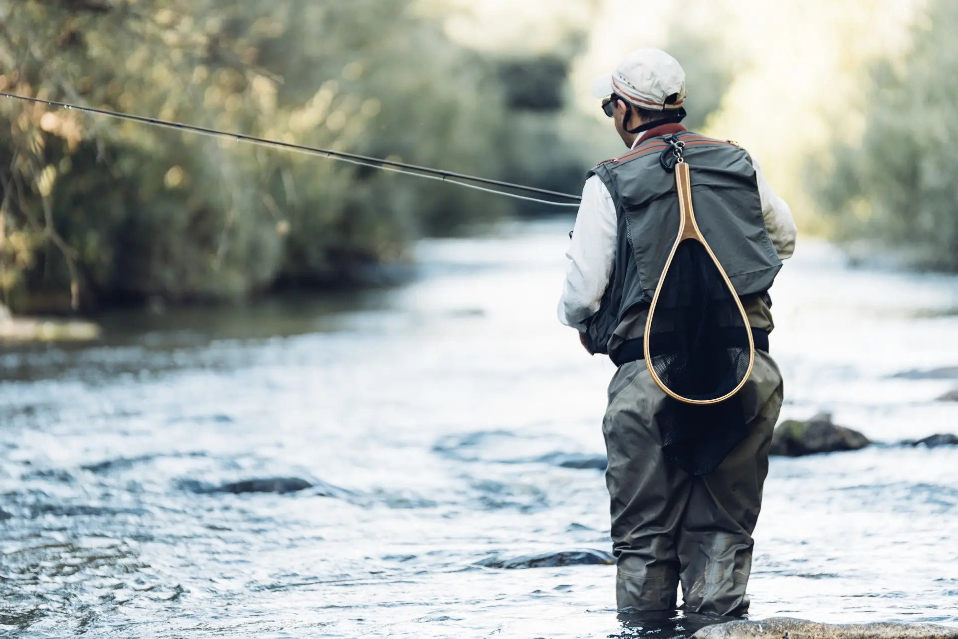 Angler wading through a river with a landing net
